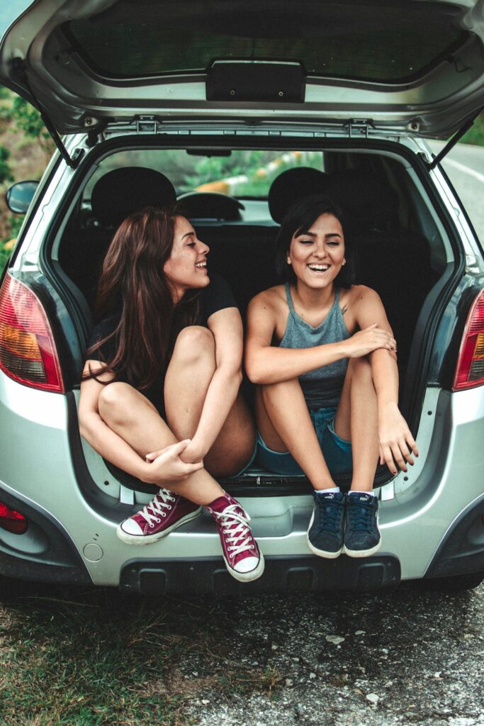 A person reviewing a printed auto insurance policy beside their parked car in a suburban driveway.