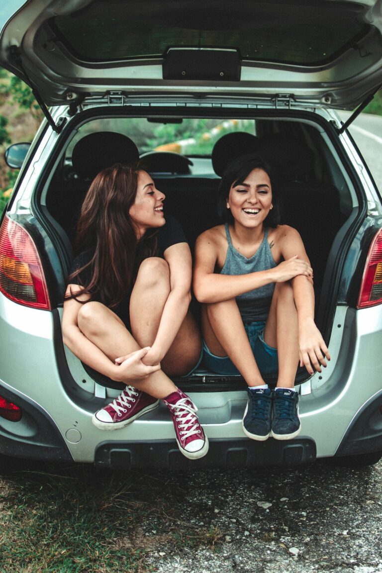 A person reviewing a printed auto insurance policy beside their parked car in a suburban driveway.