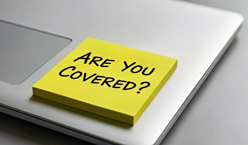 A couple reviews life insurance paperwork beside medication bottles and a notebook at a kitchen table.